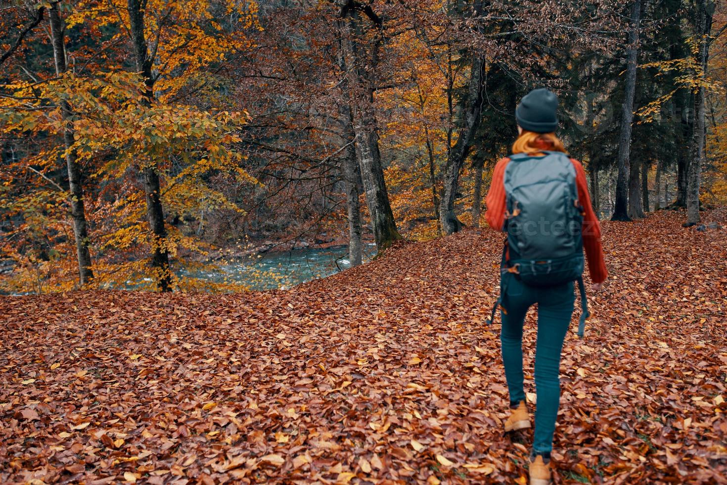 vrouw toerist met een rugzak wandelen in de park met gedaald bladeren in herfst in natuur foto