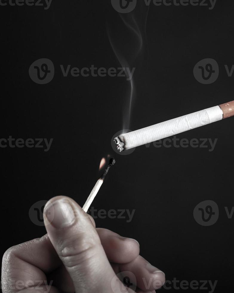 het aansteken van een sigaret met een brandende lucifer in zwart-wit foto