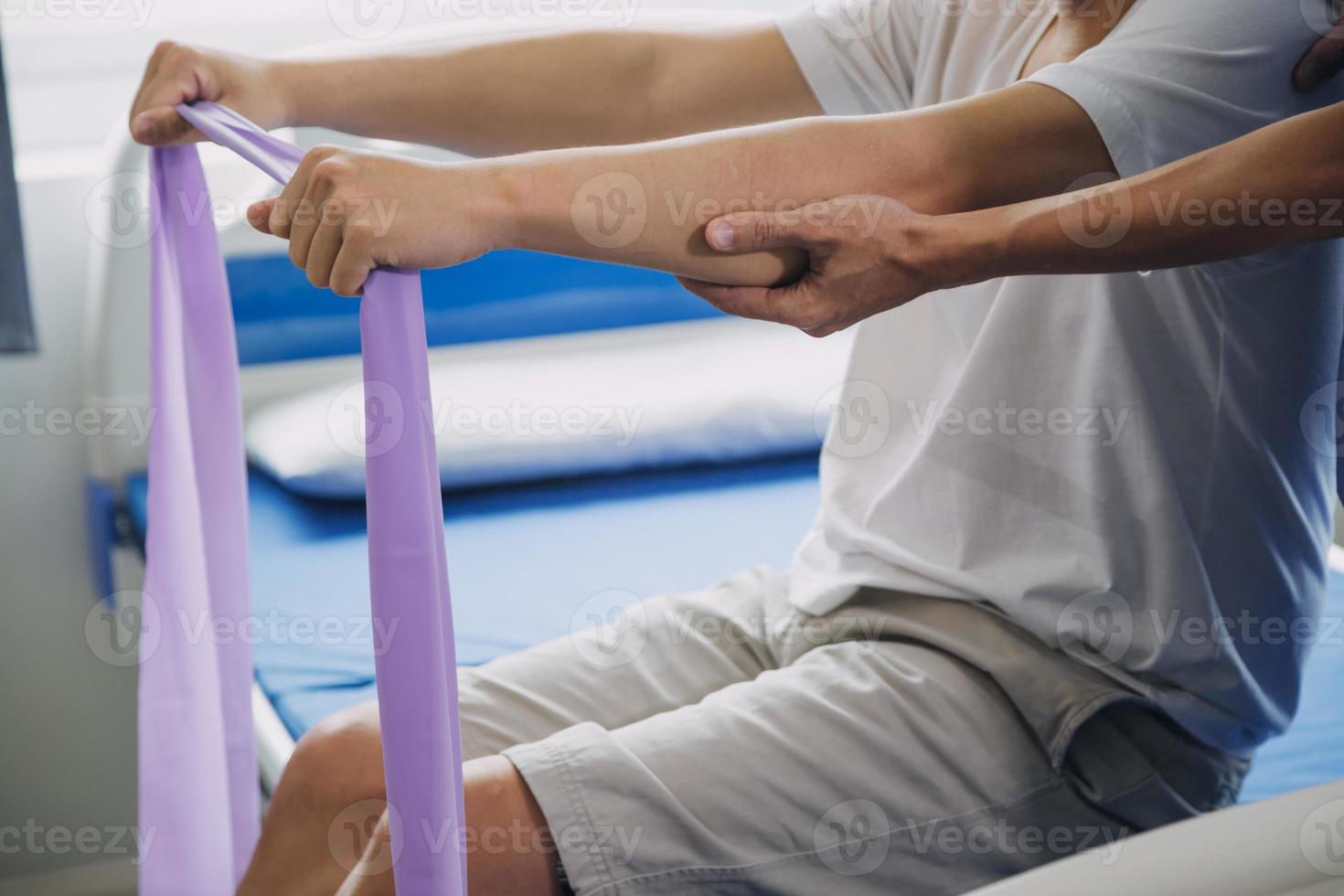 dokter of fysiotherapeut werken onderzoeken behandelen gewond arm van atleet mannetje geduldig, uitrekken en oefening, aan het doen de revalidatie behandeling pijn in kliniek. foto