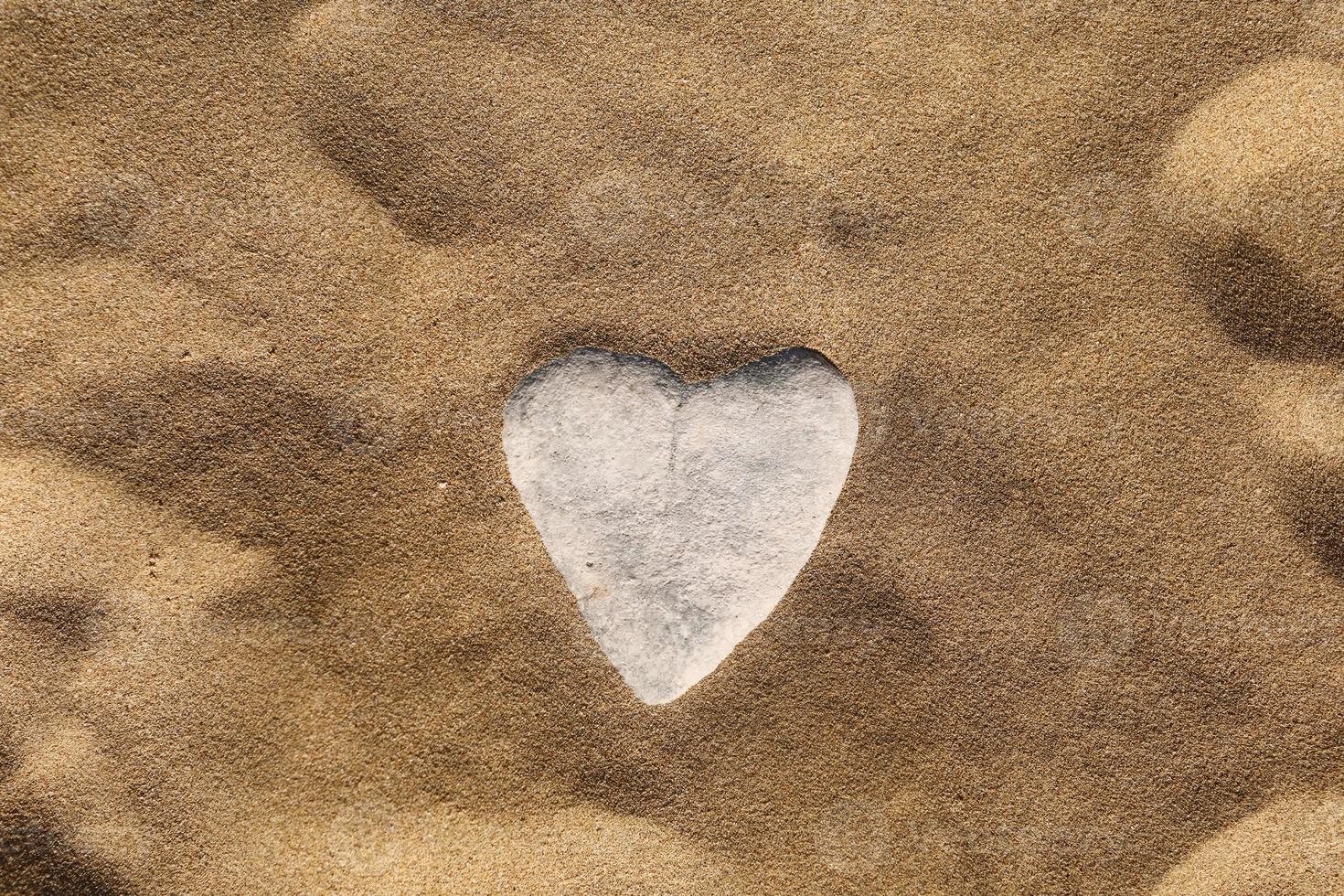 steen in de vorm van een hart op zand. zeezand achtergrond, behang. Valentijnsdag, bruiloft, huwelijksreis of liefde wenskaart concept. foto