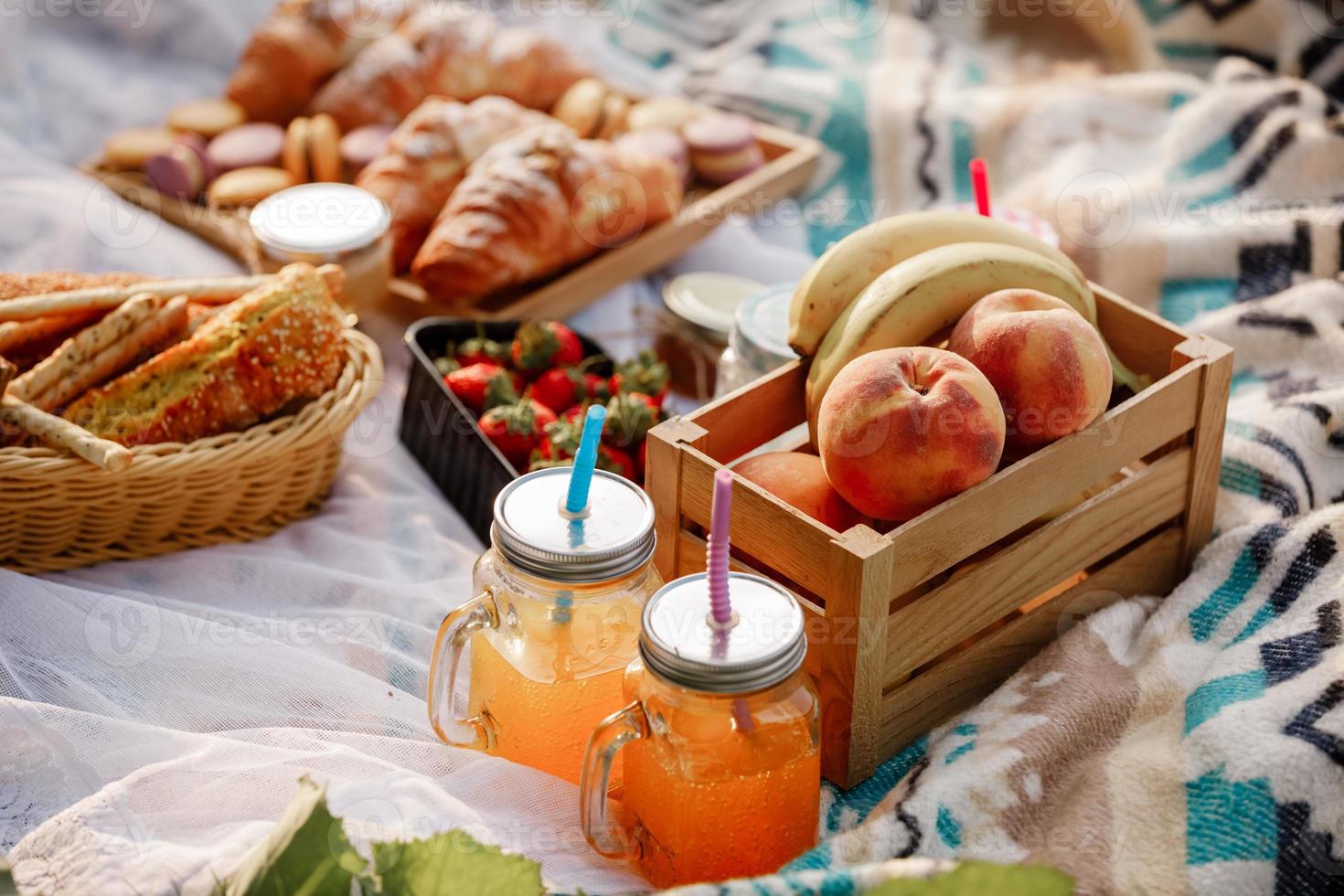 picknick in het park. vers fruit, ijskoude mousserende drankjes en croissants op een warme zomerdag. Picnic lunch. selectieve aandacht. foto