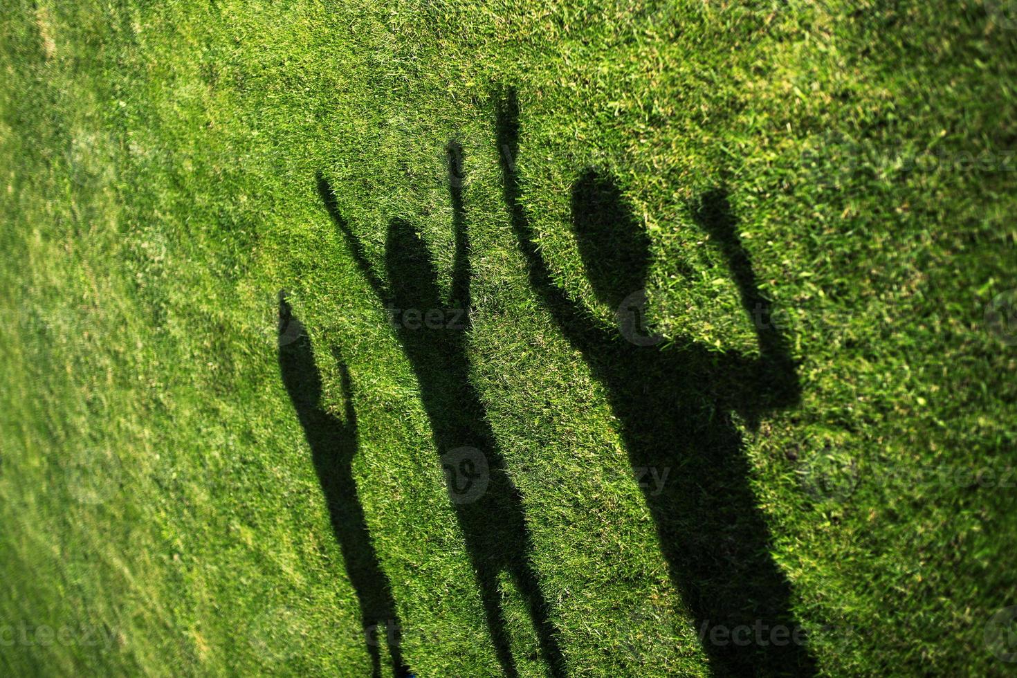 silhouet van drie mensen staan met hun handen gestrekt op groen gras foto