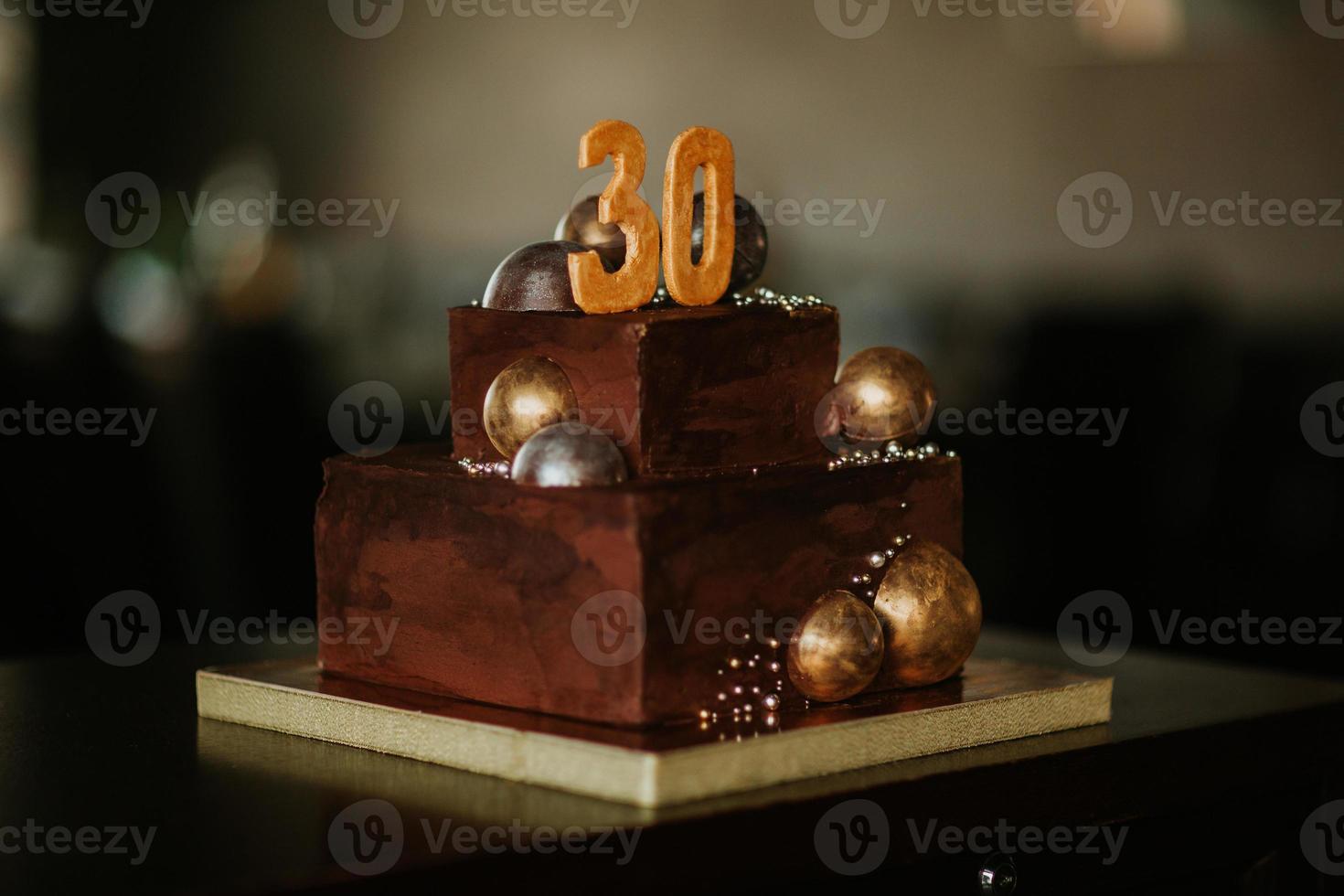 chocolade verjaardagstaart met een nummer 30 versierd met gouden chocoladeballen. foto