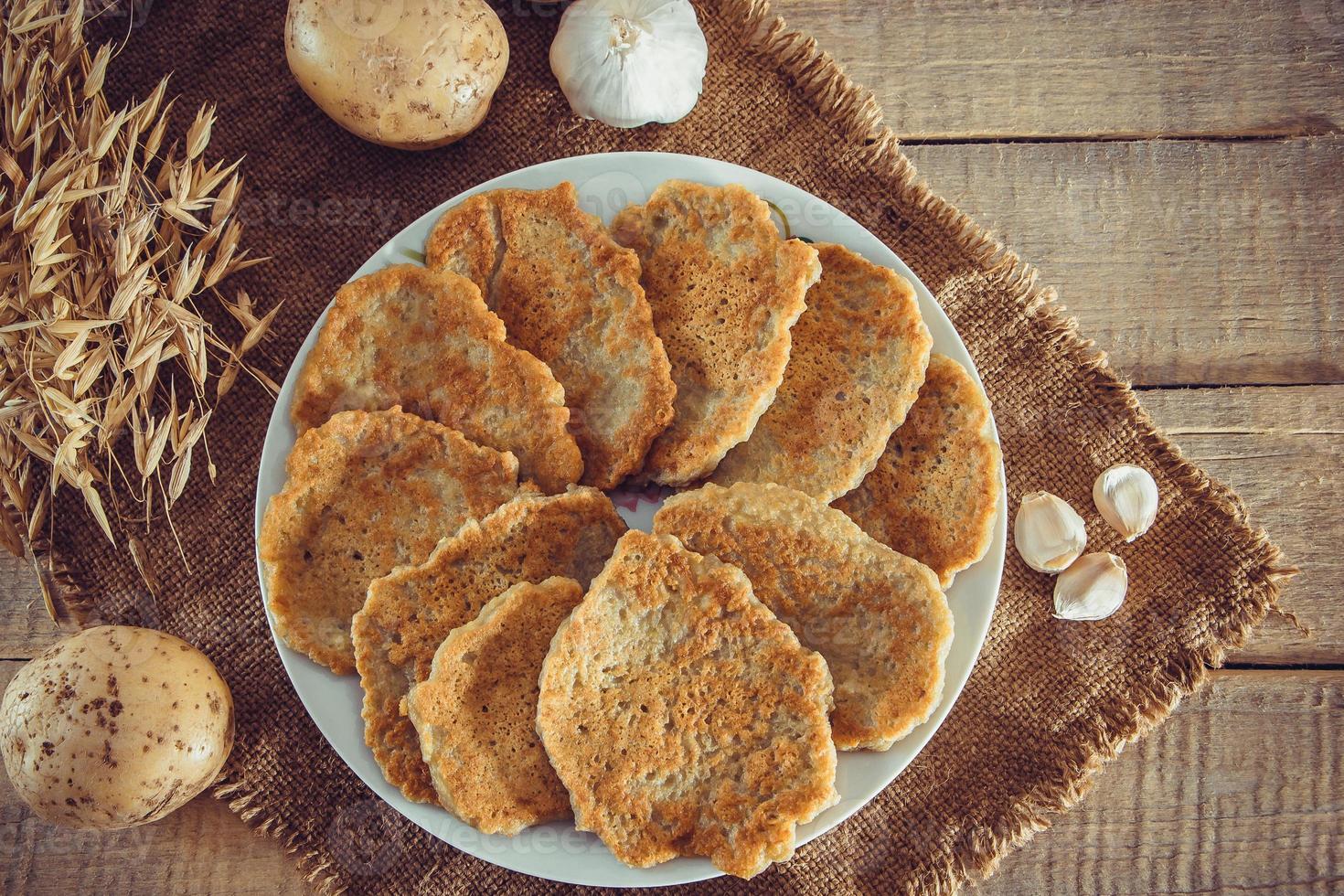 Oekraïense voedselaardappelpannenkoekjes op een plaat en een vork op linnenachtergrond foto