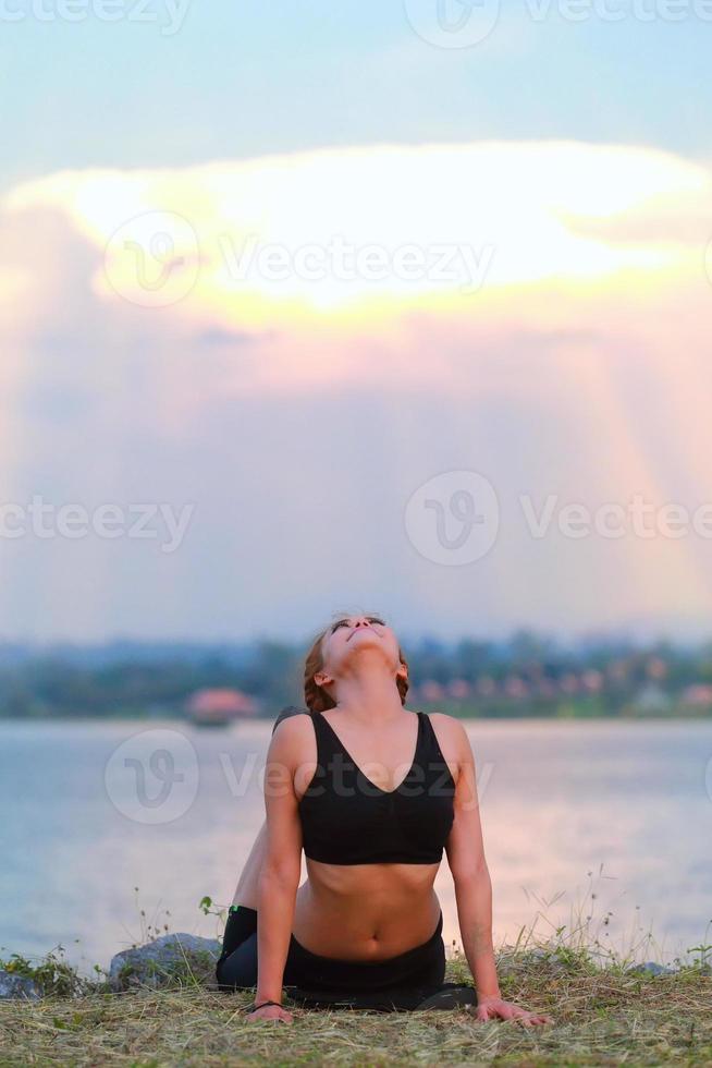 jong meisje aan het doen yoga geschiktheid oefening ochtend- zonsopkomst buitenshuis in de weide mooi bergen landschap. meditatie en kom tot rust. foto