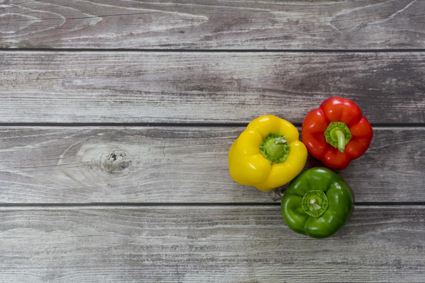 rode, groene en gele peper, op een houten tafel. foto