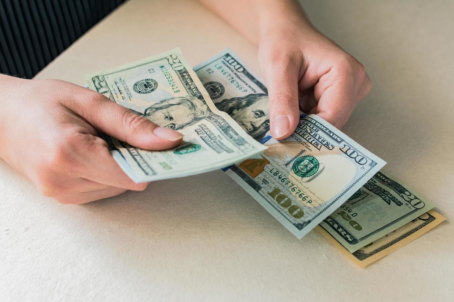 vrouw handen tellen dollarbiljetten op wit bureau foto
