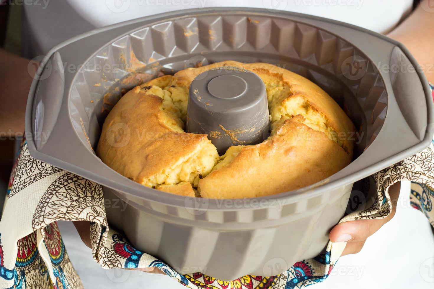 handen van een persoon die een siliconen mal met zelfgemaakte cake met veelkleurige handdoek vasthoudt. selectieve aandacht foto