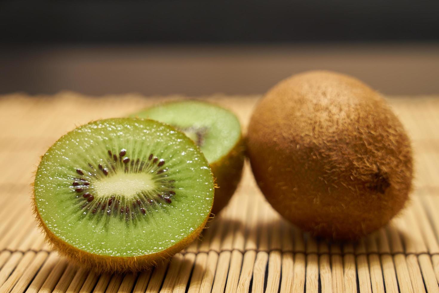 rijpe bruine kiwi en gesneden groene kiwi close-up op een rietje achtergrond. foto