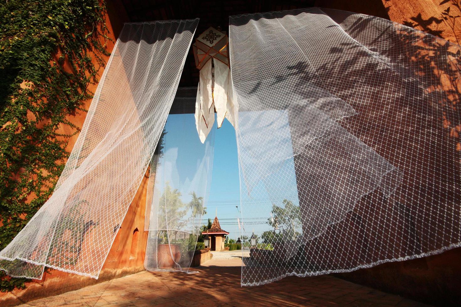 wit zijde gordijnen in de wind decoratie in de tropisch lanna tuin van Thailand foto