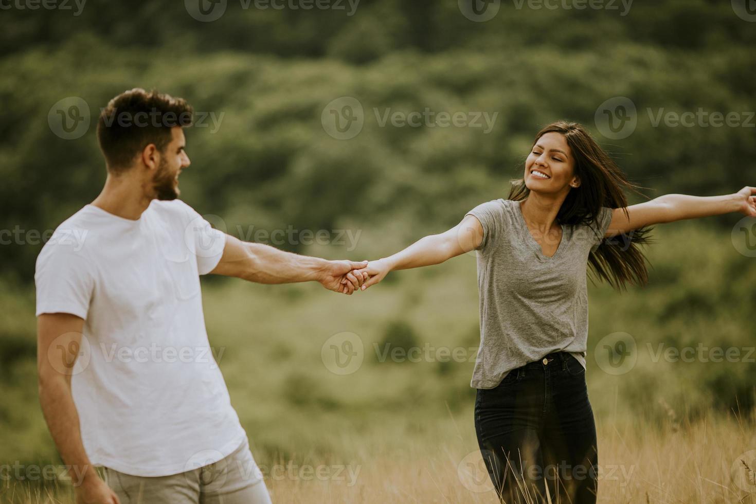 gelukkig jong koppel verliefd wandelen door grasveld foto