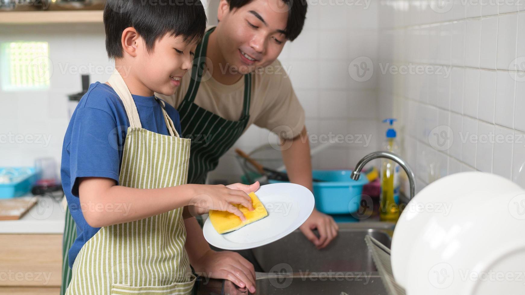 gelukkig glimlachen jong Aziatisch vader en zoon het wassen gerechten in keuken Bij huis foto