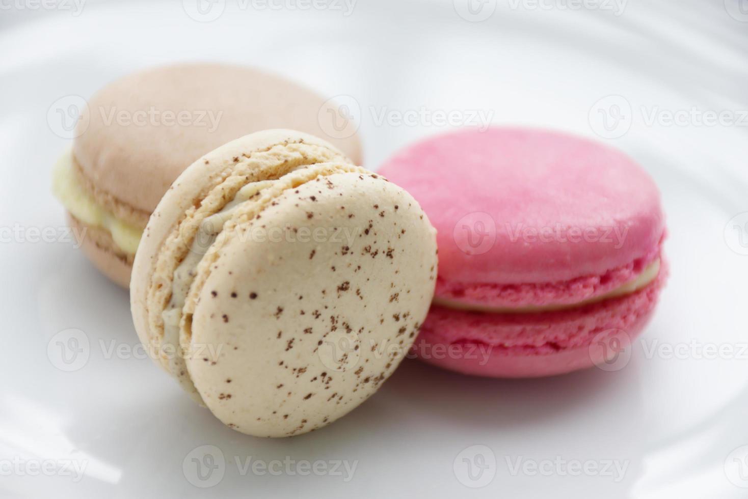 drie kleurrijk macarons dat zijn heerlijk naar eten. zetten Aan een wit bord. foto