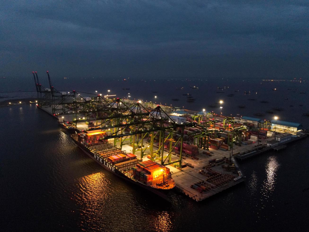 Jakarta, Indonesië 2021 - luchtfoto van het laden en lossen van containerschepen in de diepzeehaven, logistieke import en export van vrachtvervoer per containerschip op open zee 's nachts foto