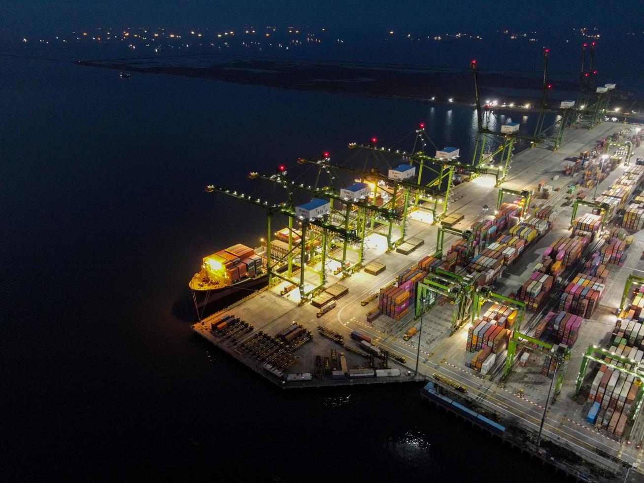 Jakarta, Indonesië 2021 - luchtfoto van het laden en lossen van containerschepen in de diepzeehaven, logistieke import en export van vrachtvervoer per containerschip op open zee 's nachts foto