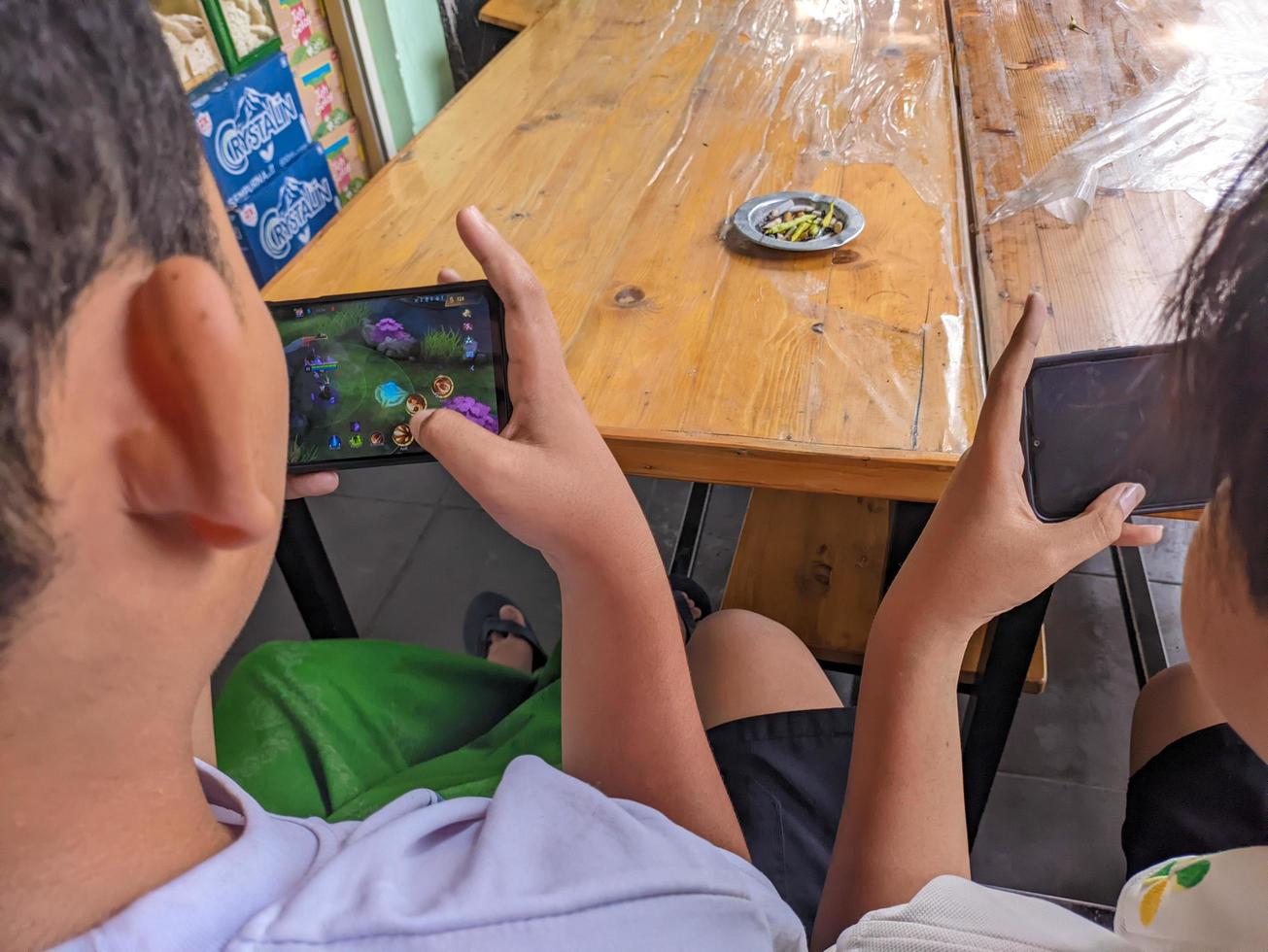 soera, Indonesië - april, 2023 - een Aziatisch jongen spelen mobiel legends spellen Aan smartphone foto