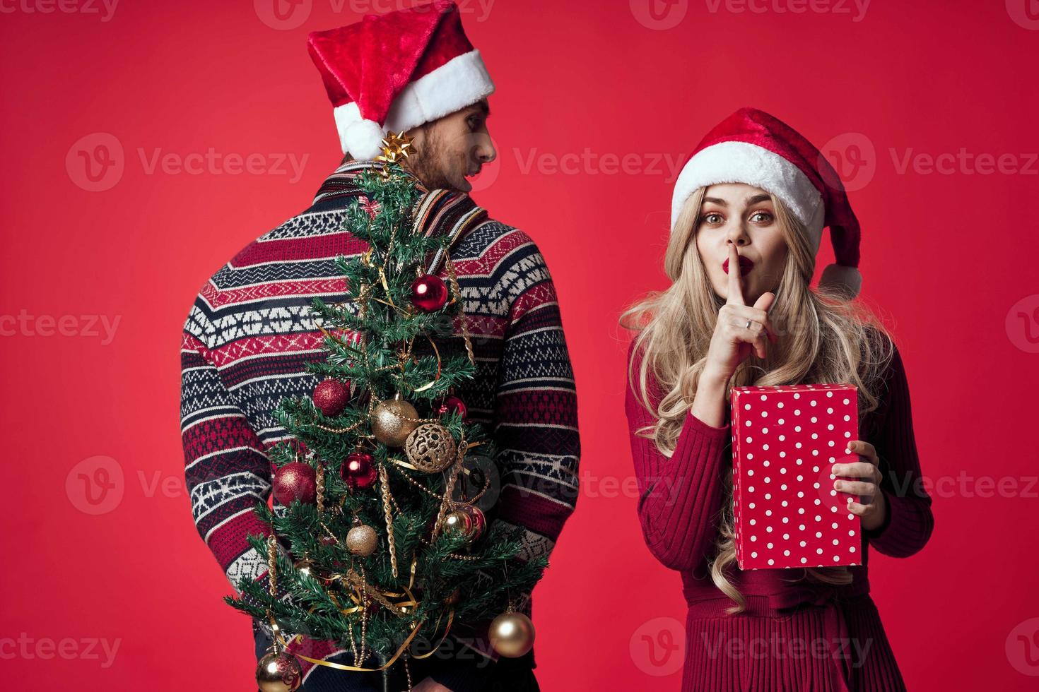 Mens en vrouw Kerstmis boom speelgoed cadeaus vakantie rood achtergrond foto