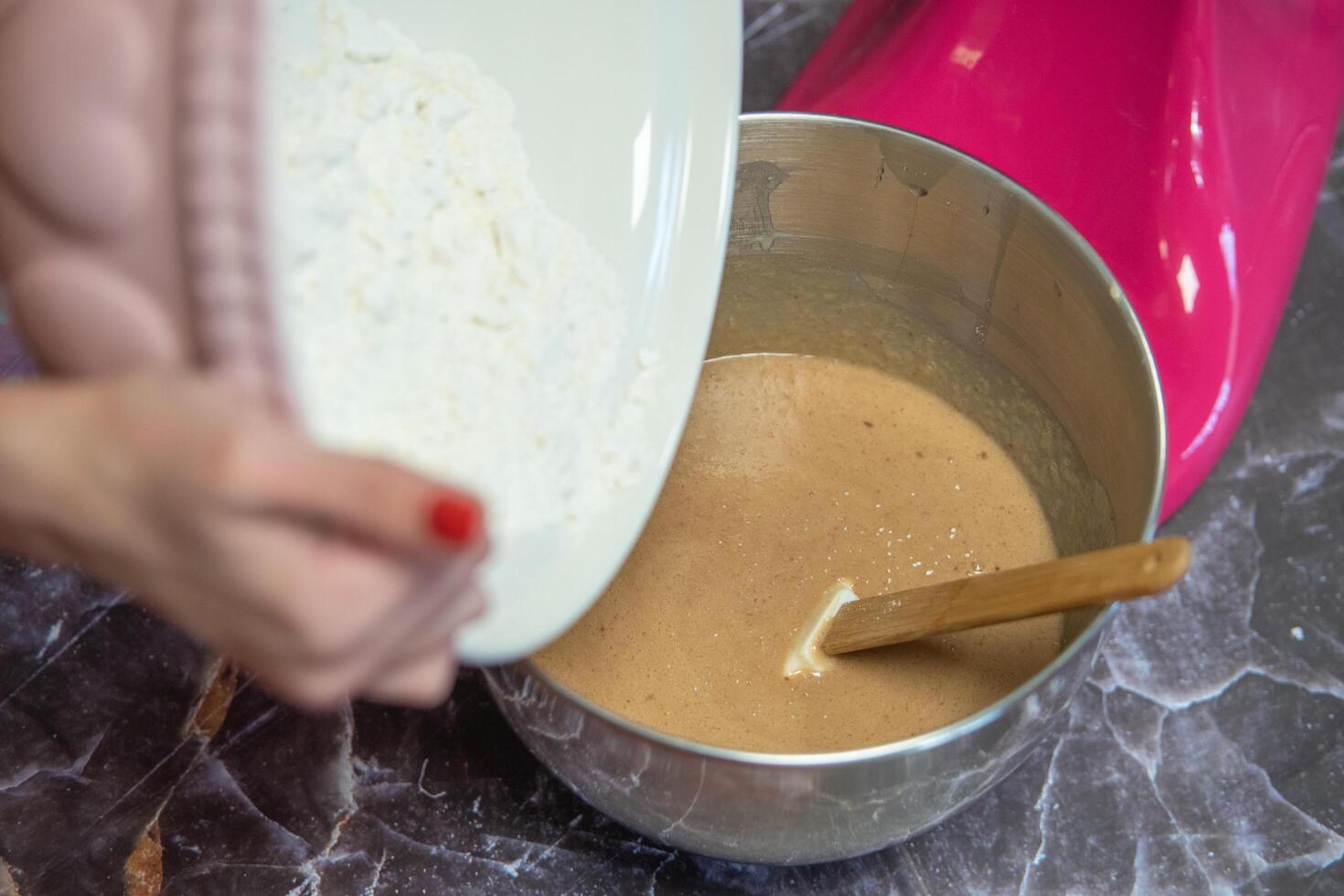 vrouw handen bloem gieten in een metalen kom voor mixer foto