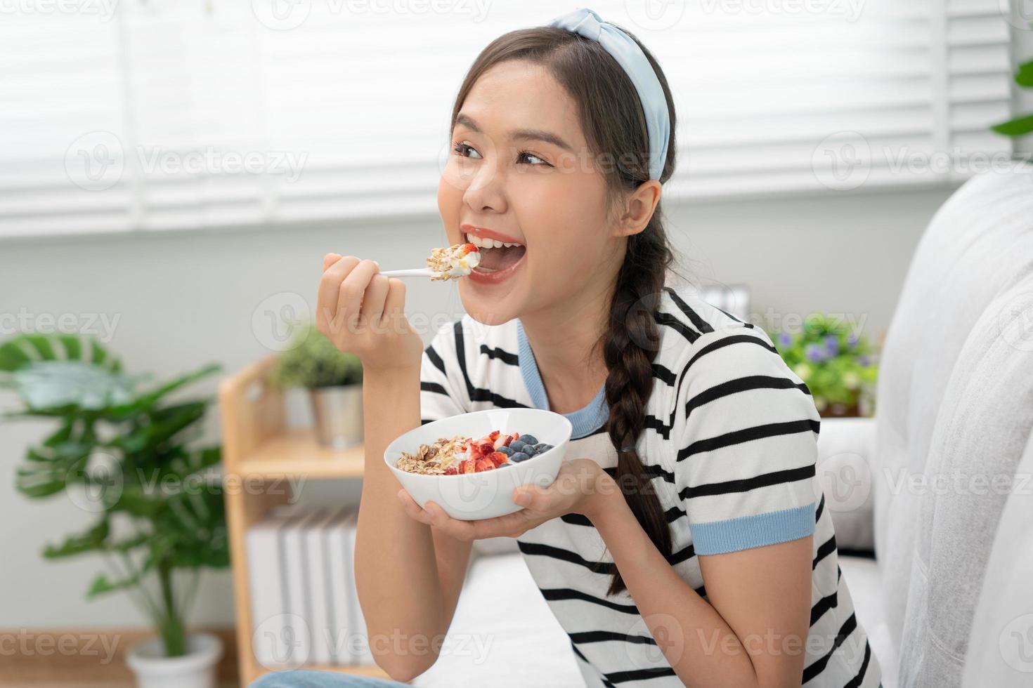 gezond voedsel. mooi vrouw meisje genieten eten yoghurt, muesli, vers fruit Aan ontbijt Gezondheid in huis. gelukkig jong vrouw glimlach Aan ochtend- mooi zo emotie. diëten, ontgiften, eetpatroon, schoon eten, vegetarisch foto