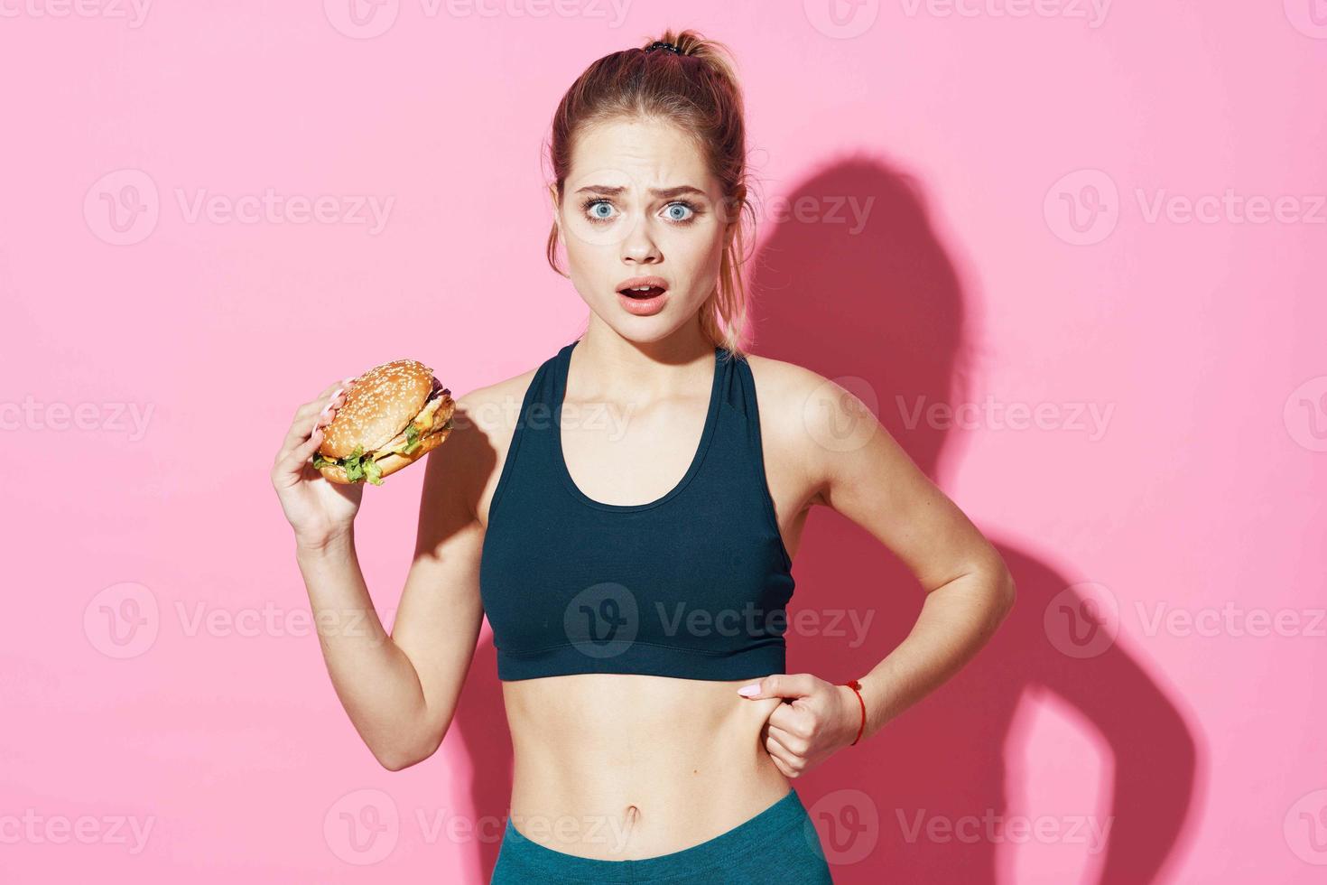 sportief vrouw training Hamburger snel voedsel eetpatroon roze achtergrond foto