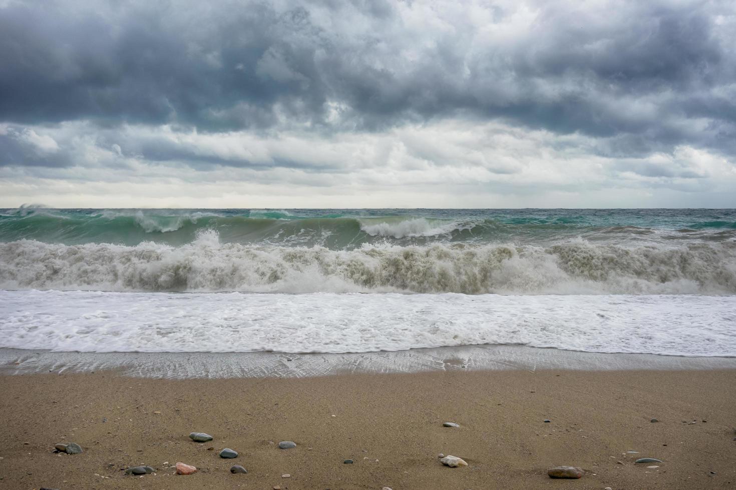 zeegezicht met beukende golven op het strand en donkere stormachtige wolken foto