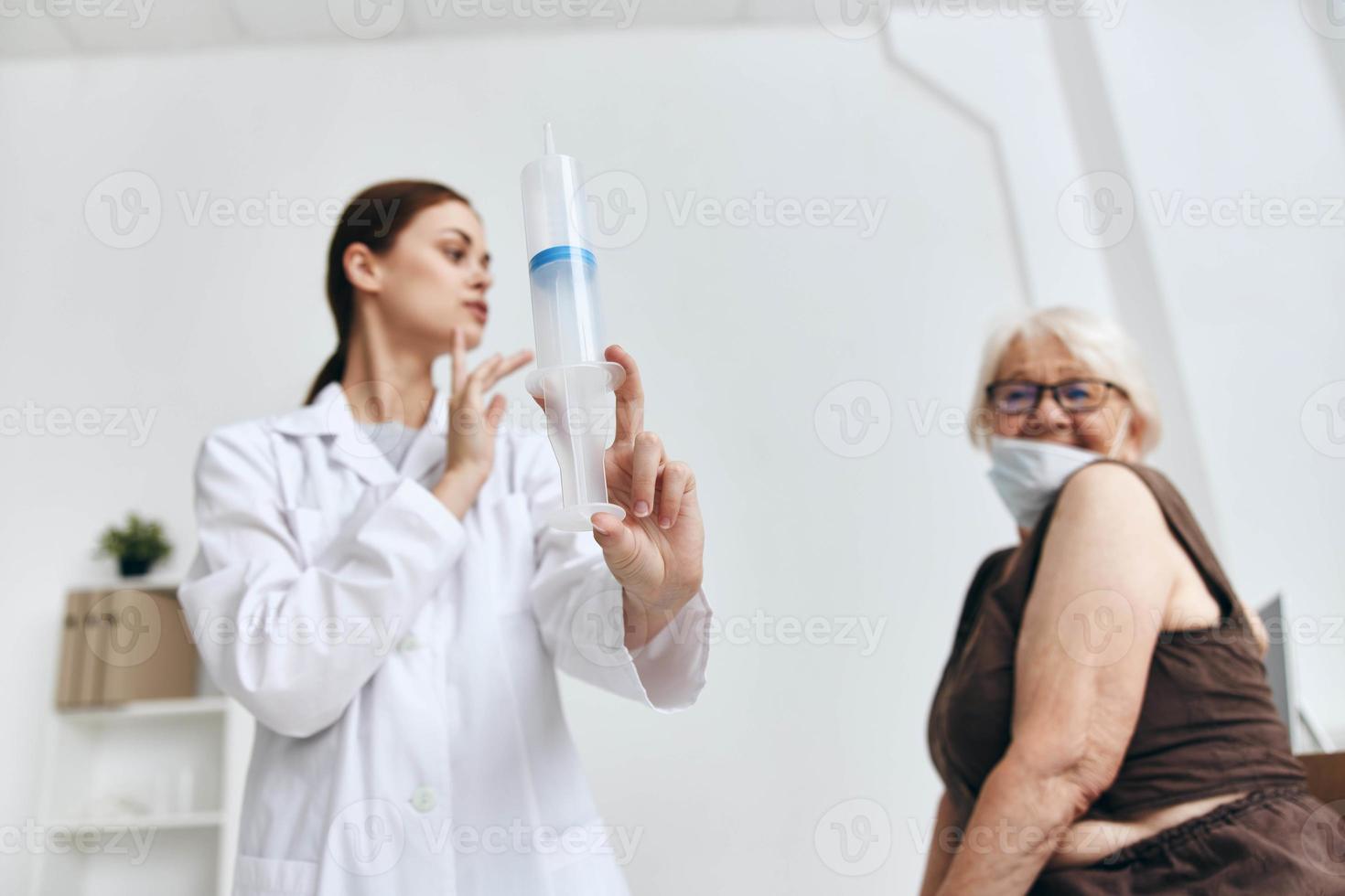 verpleegster geven een injectie naar een ouderen vrouw in de arm pret foto