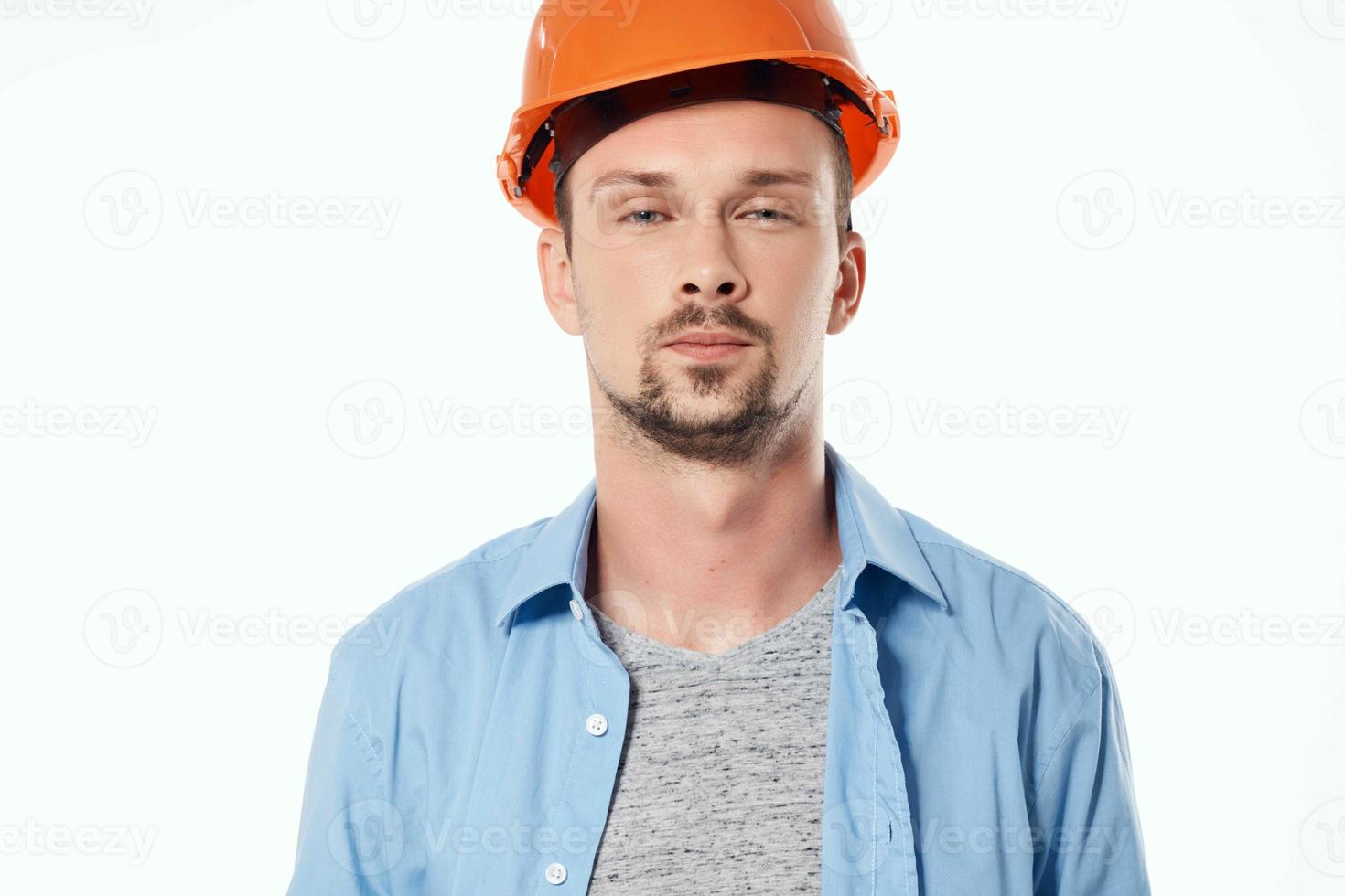 Mens in oranje helm blauwdrukken bouwer licht achtergrond foto