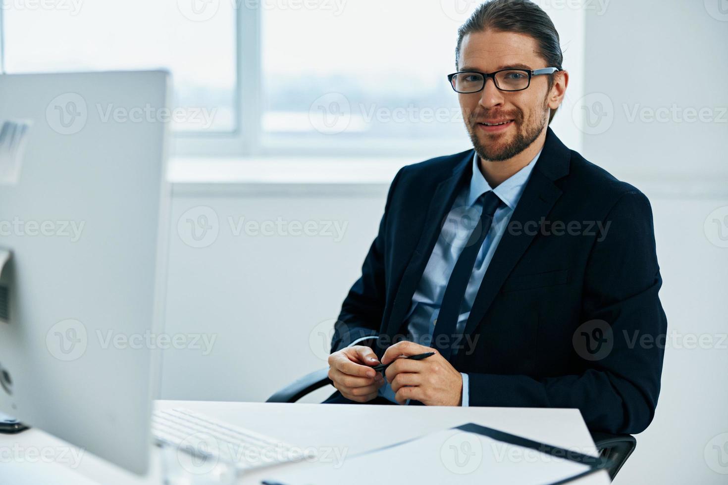 Mens in een pak werk in voorkant van een computer documenten uitvoerend foto