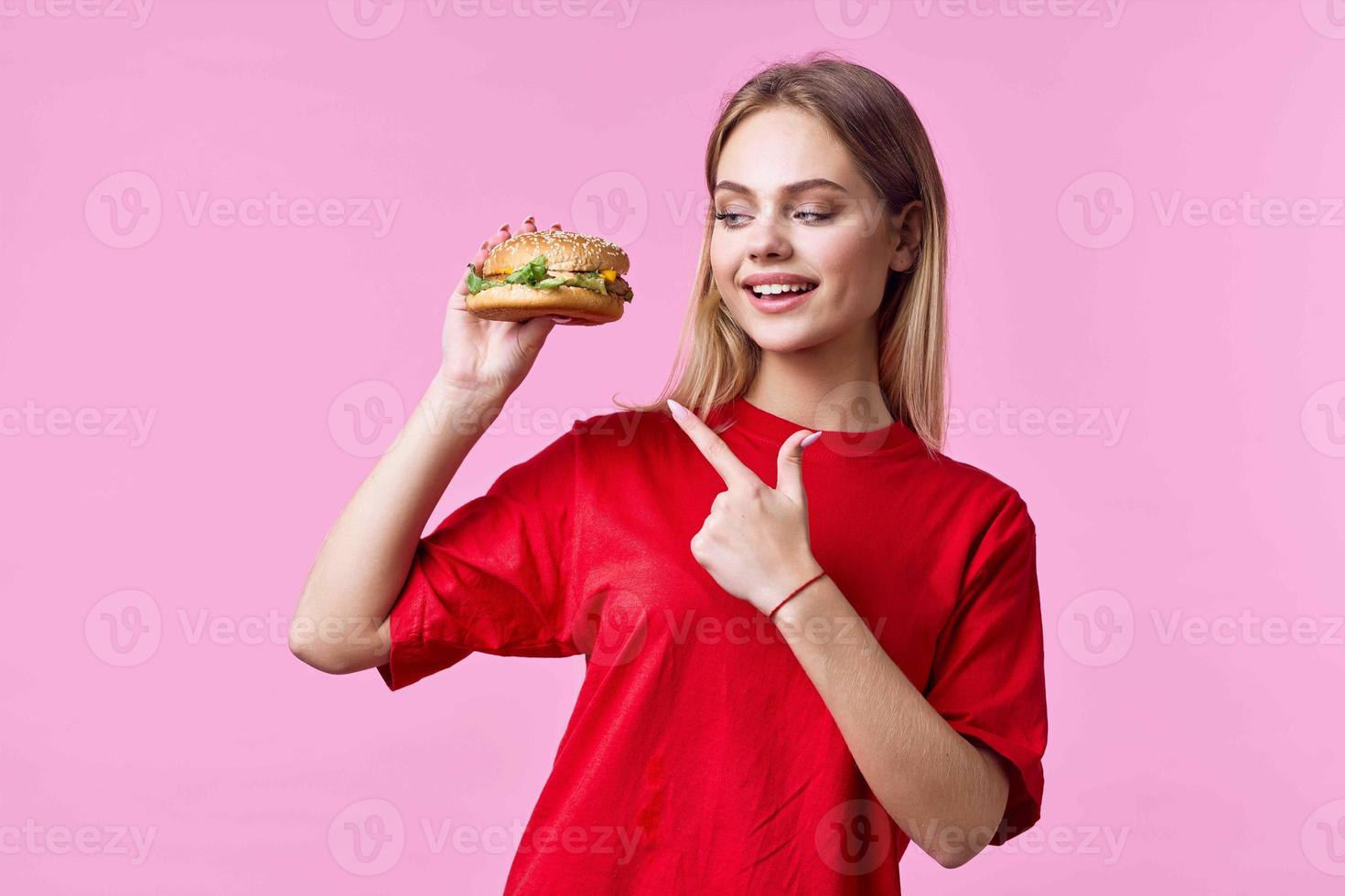 vrouw in rood t-shirt snel voedsel tussendoortje roze achtergrond foto