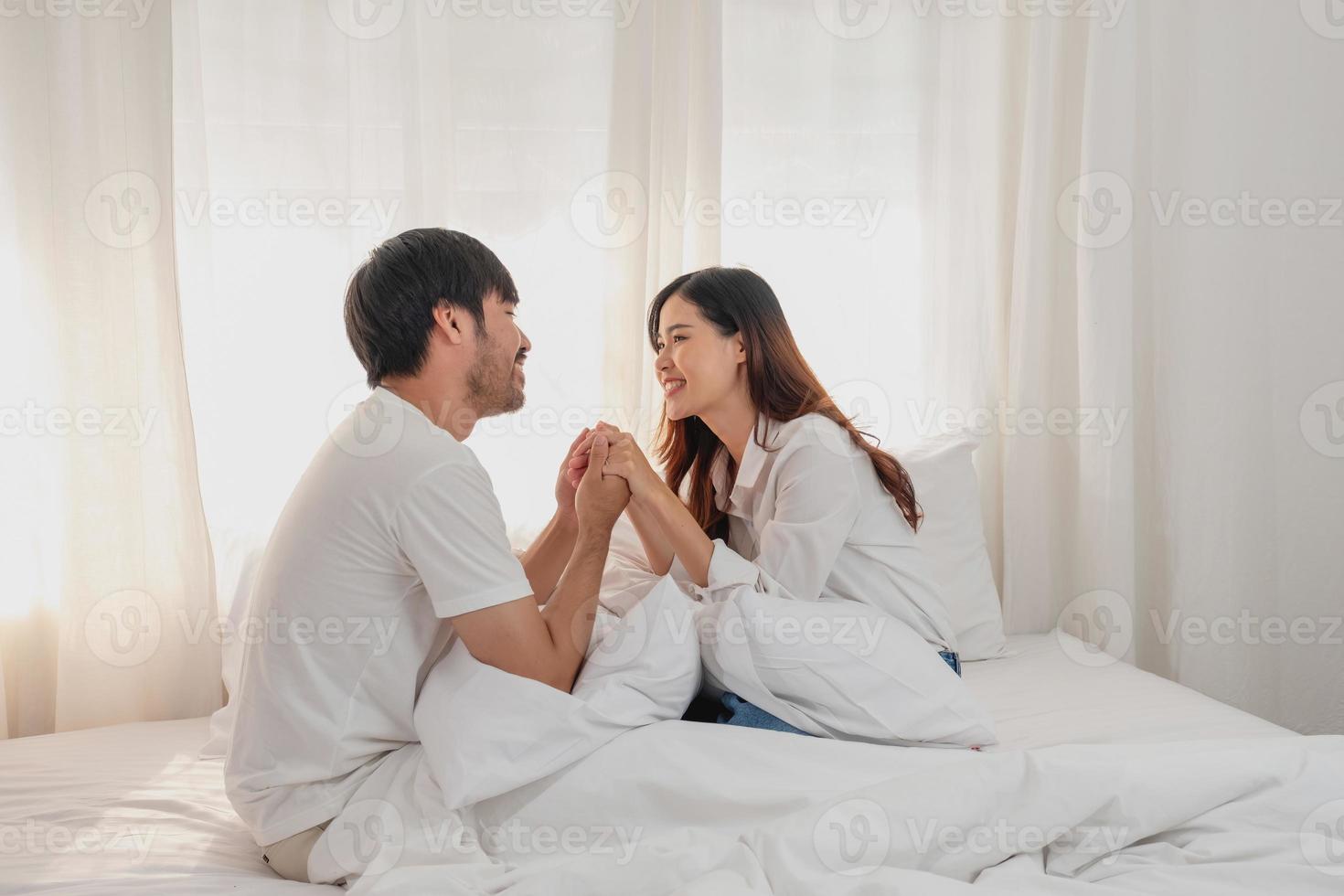 gelukkig jong Aziatisch paar omarmen, plagen, spelen vrolijk in bed Bij huis, romantisch tijd naar verbeteren familie binding. familie concept. foto