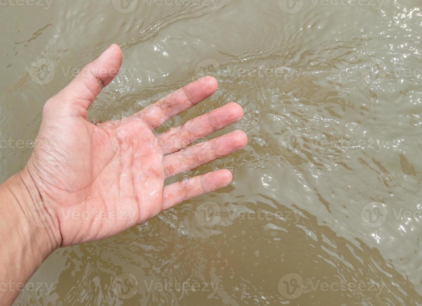de hand- van een jong Mens is aanraken de vloeiende water. foto