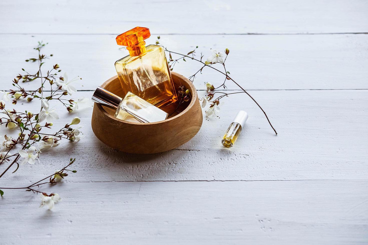 parfumflesjes met bloemen op een witte houten achtergrond foto