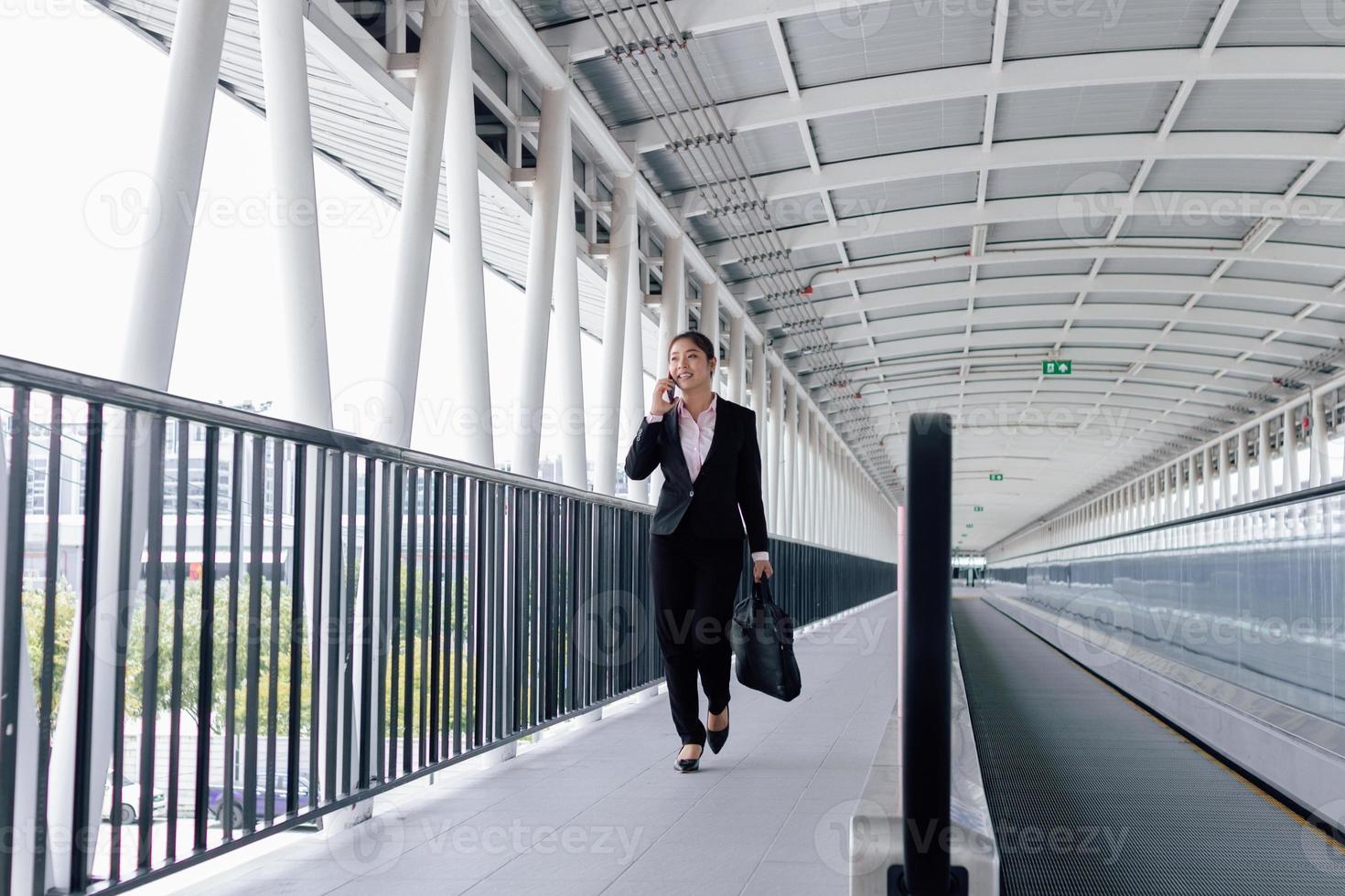 jong Aziatisch zakenvrouw in zwart pak gebruik makend van digitaal tablet en staand Aan loopbrug station met kopiëren ruimte. foto
