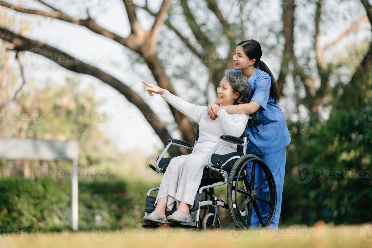 ouderen Aziatisch senior vrouw Aan rolstoel met Aziatisch voorzichtig verzorger en aanmoedigen geduldig, wandelen in tuin. met zorg van een verzorger en senior Gezondheid verzekering. foto