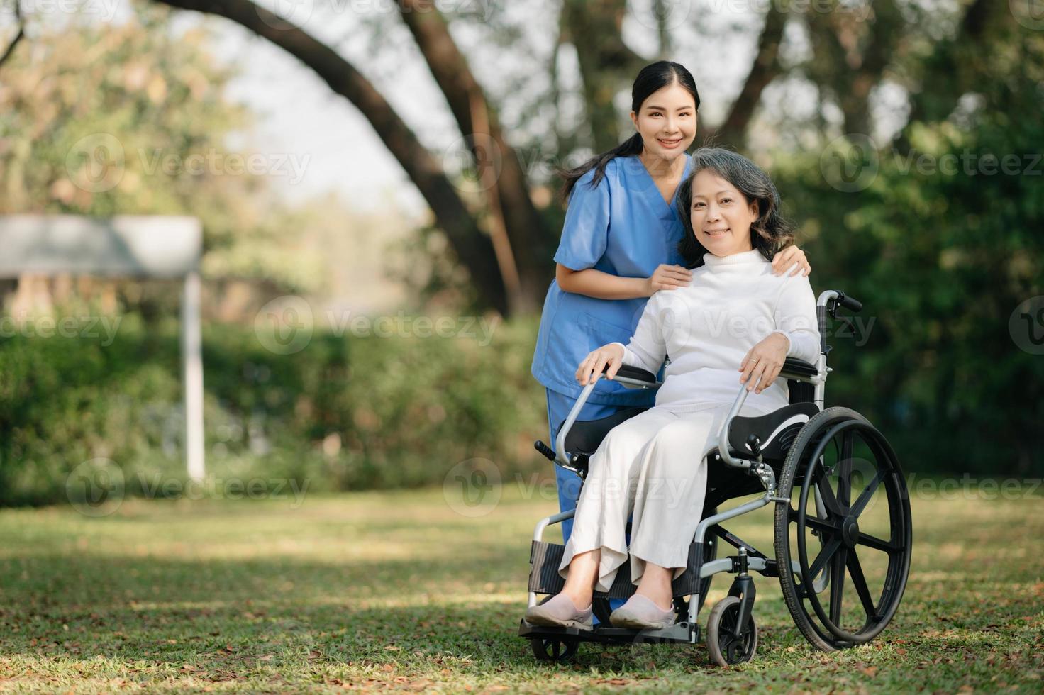 ouderen Aziatisch senior vrouw Aan rolstoel met Aziatisch voorzichtig verzorger en aanmoedigen geduldig, wandelen in tuin. met zorg van een verzorger en senior Gezondheid verzekering. foto