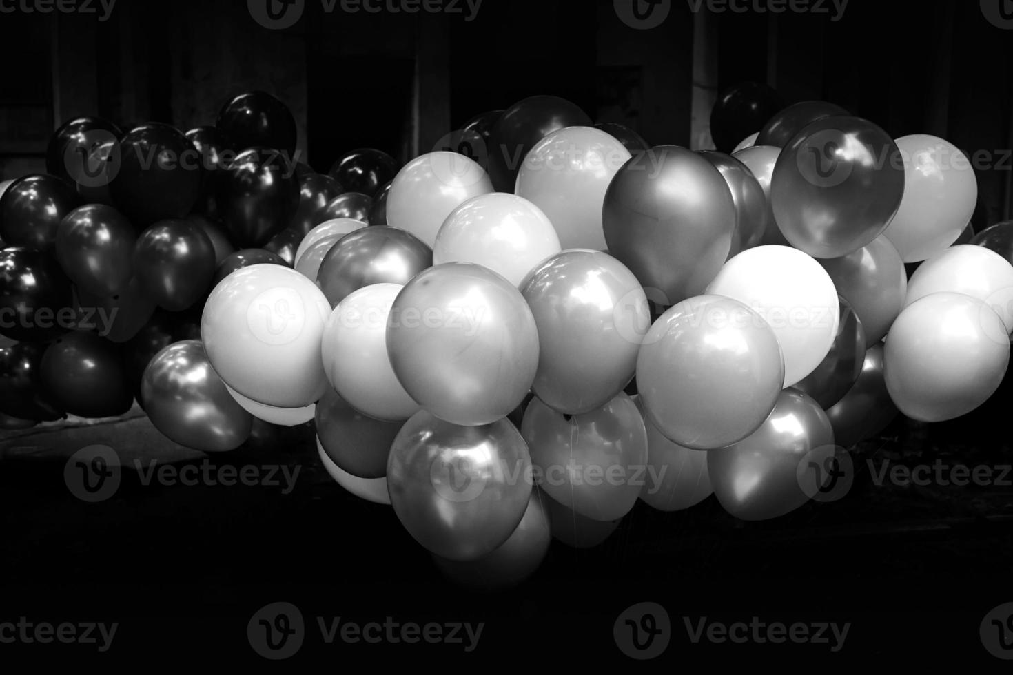 een bundel van kleurrijk met gas gevuld ballonnen Aan donker achtergrond. zwart en wit afbeelding. foto