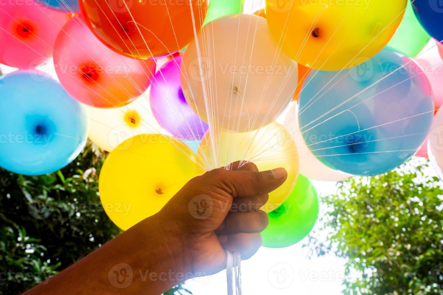 een handvol van handen is Holding een bundel van gekleurde met gas gevuld ballonnen. kleurrijk ballonnen achtergrond. foto