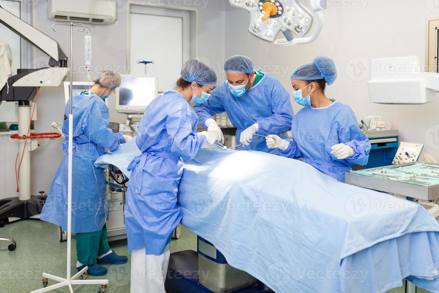 groep van medisch team dringend aan het doen chirurgisch operatie en helpen geduldig in theater Bij ziekenhuis. medisch team het uitvoeren van chirurgisch operatie in een helder modern in werking kamer foto