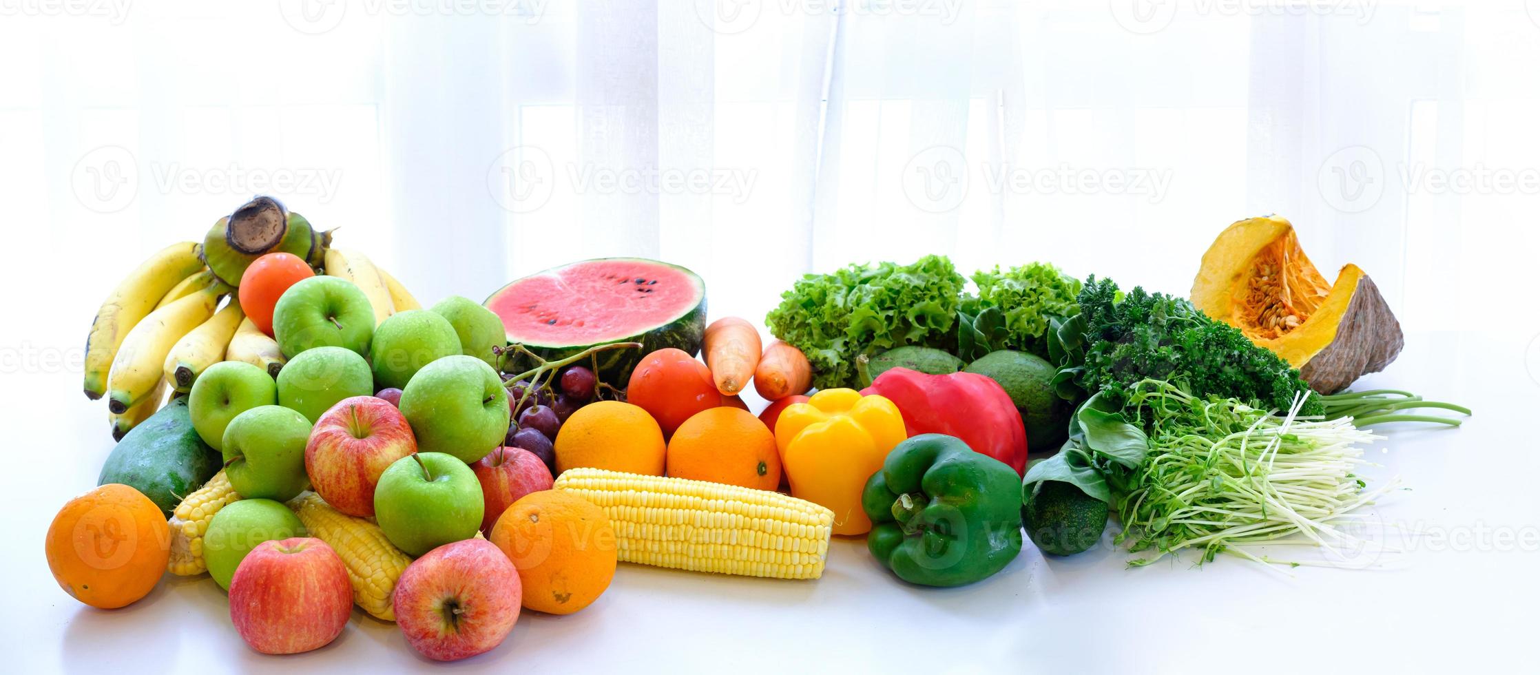 geassorteerde verse rijpe groenten en fruit op tafel met witte gordijn achtergrond foto