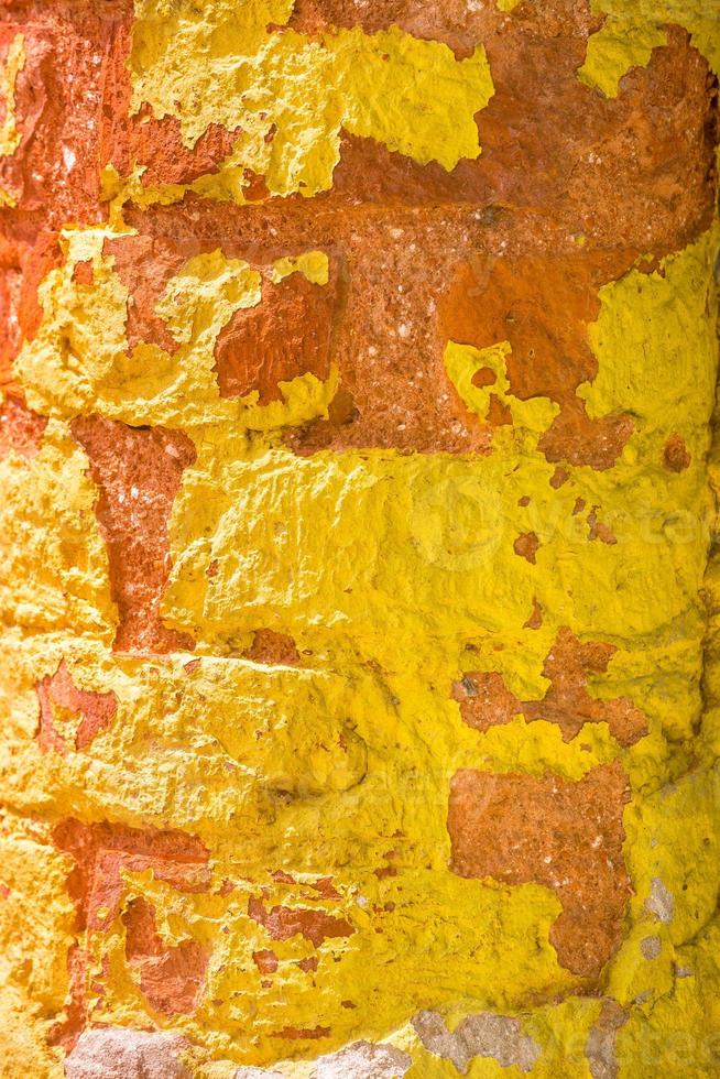 rood, oranje, geel en blauw kleur combinatie oud getextureerde schade muur met kleurrijk bakstenen. foto