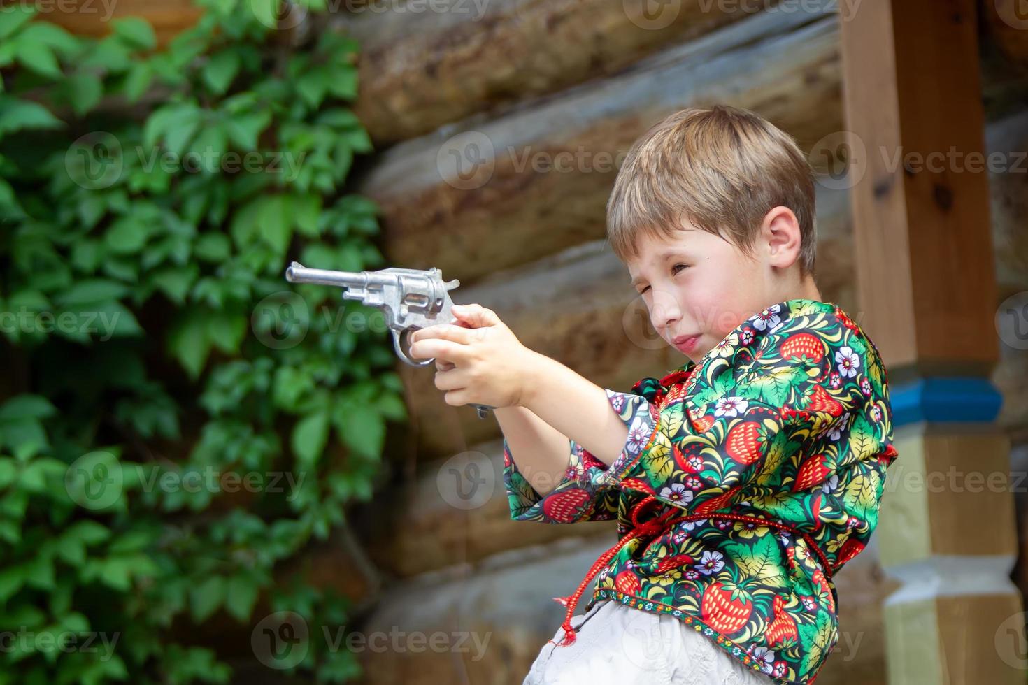 Russisch jongen in nationaal jurk met een pistool. foto