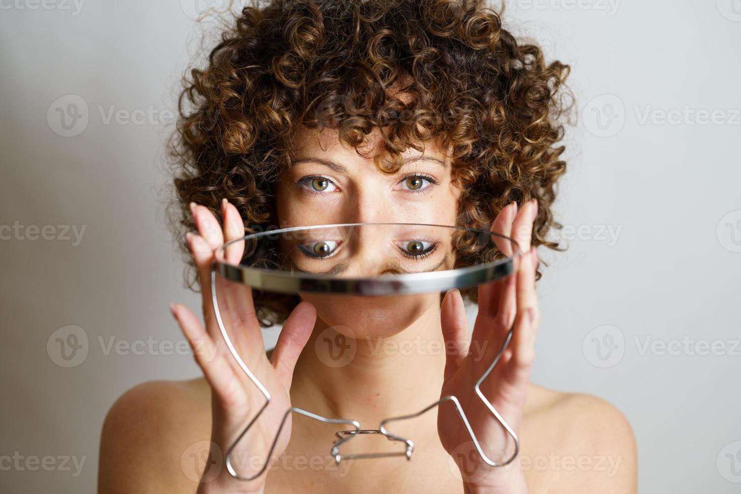 vrouw met gekruld haar- Holding spiegel in handen foto