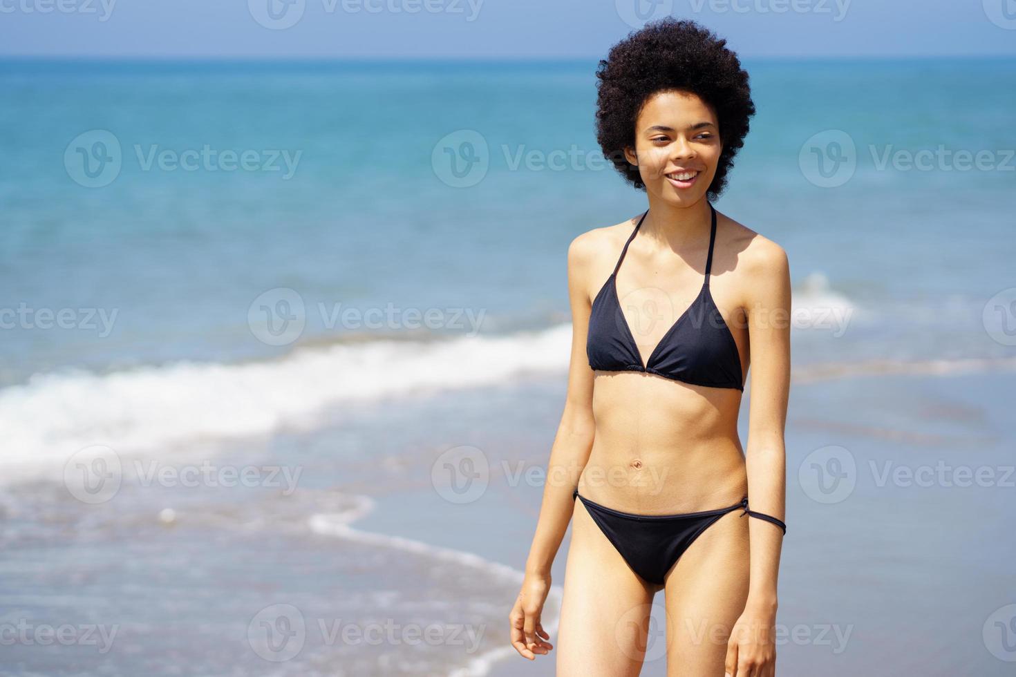 inhoud zwart vrouw in bikini wandelen Aan kust foto