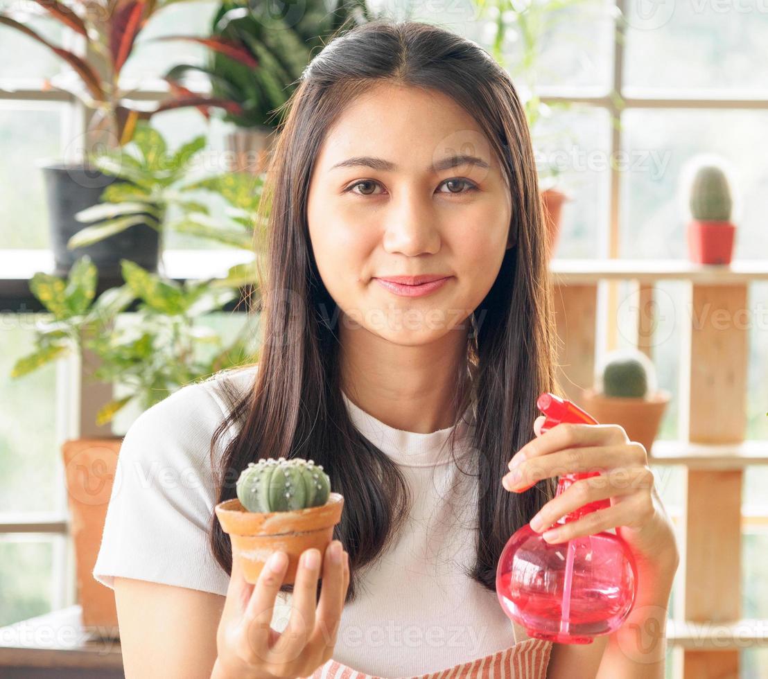 portret tuin mooi mooi jong Aziatisch meisje vrouw vervelend wit blouse met lang zwart haar- en glimlach vers met helder glimlach kijken pot klein boom blad groen fabriek in kamer winkel gelukkig en kom tot rust foto