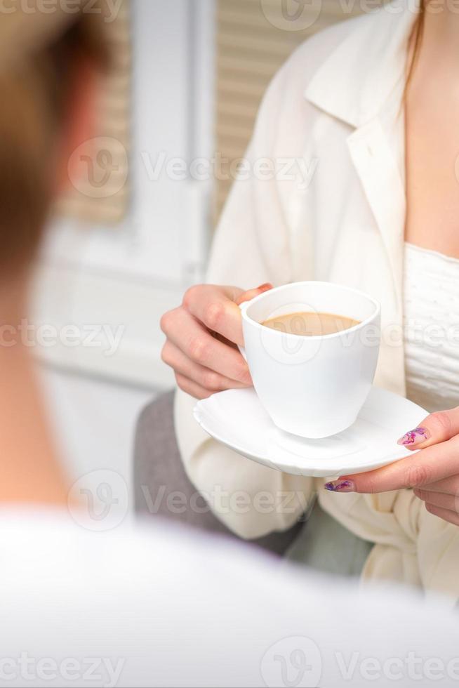 jong Kaukasisch onherkenbaar vrouw Holding een kop van heet drinken Bij een dokter afspraak in ziekenhuis kantoor. foto