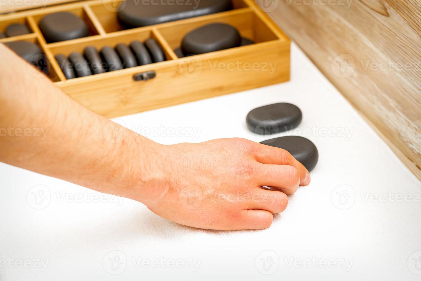 hand- van masseur duurt zwart massage stenen van de tafel in spa salon. foto