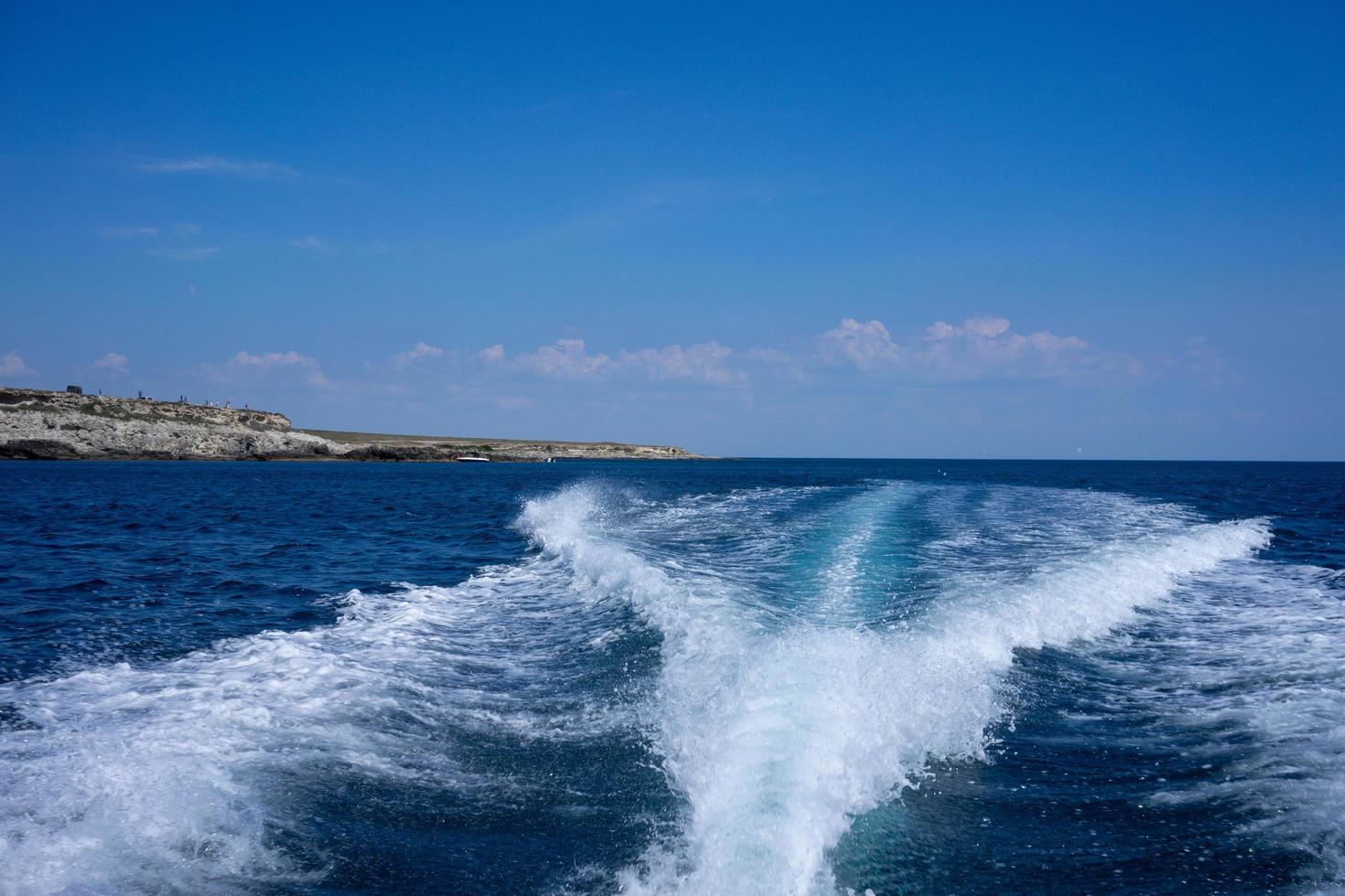 uitzicht op het kielzog van een boot op het water met bewolkte blauwe hemel foto