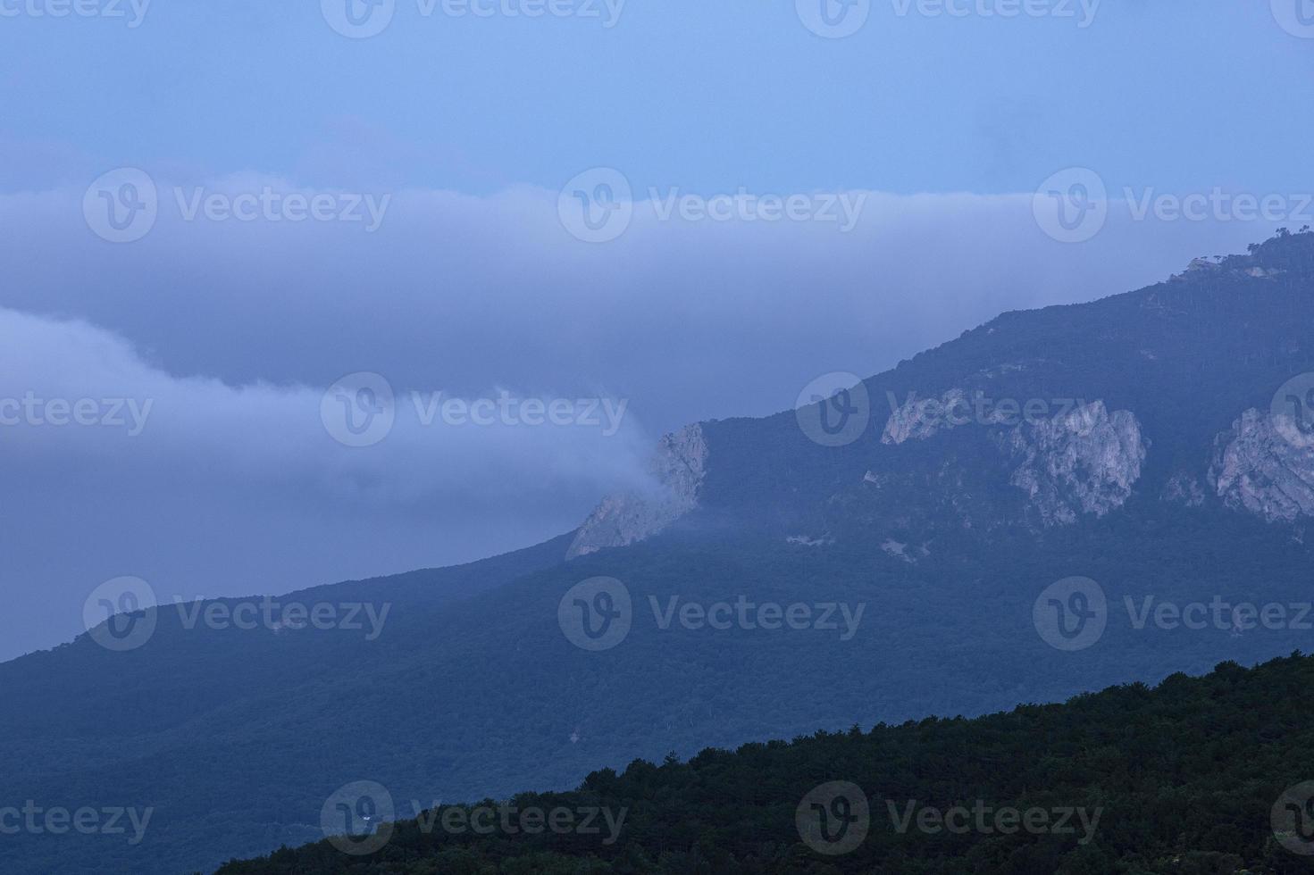 berg landschap, wolken Aan top van een berg reeks afdalen vlot naar beneden. foto