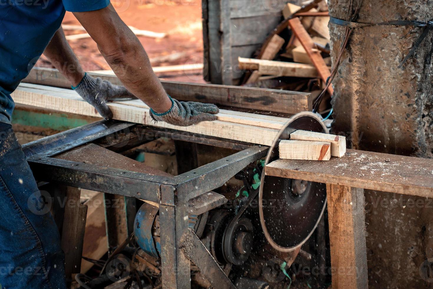 detailopname van een arbeiders handen snijdend hout met een circulaire zag in een zagerij. foto