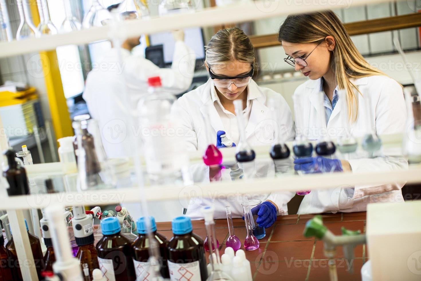 vrouwelijke onderzoekers in witte laboratoriumjas die in het laboratorium werken foto